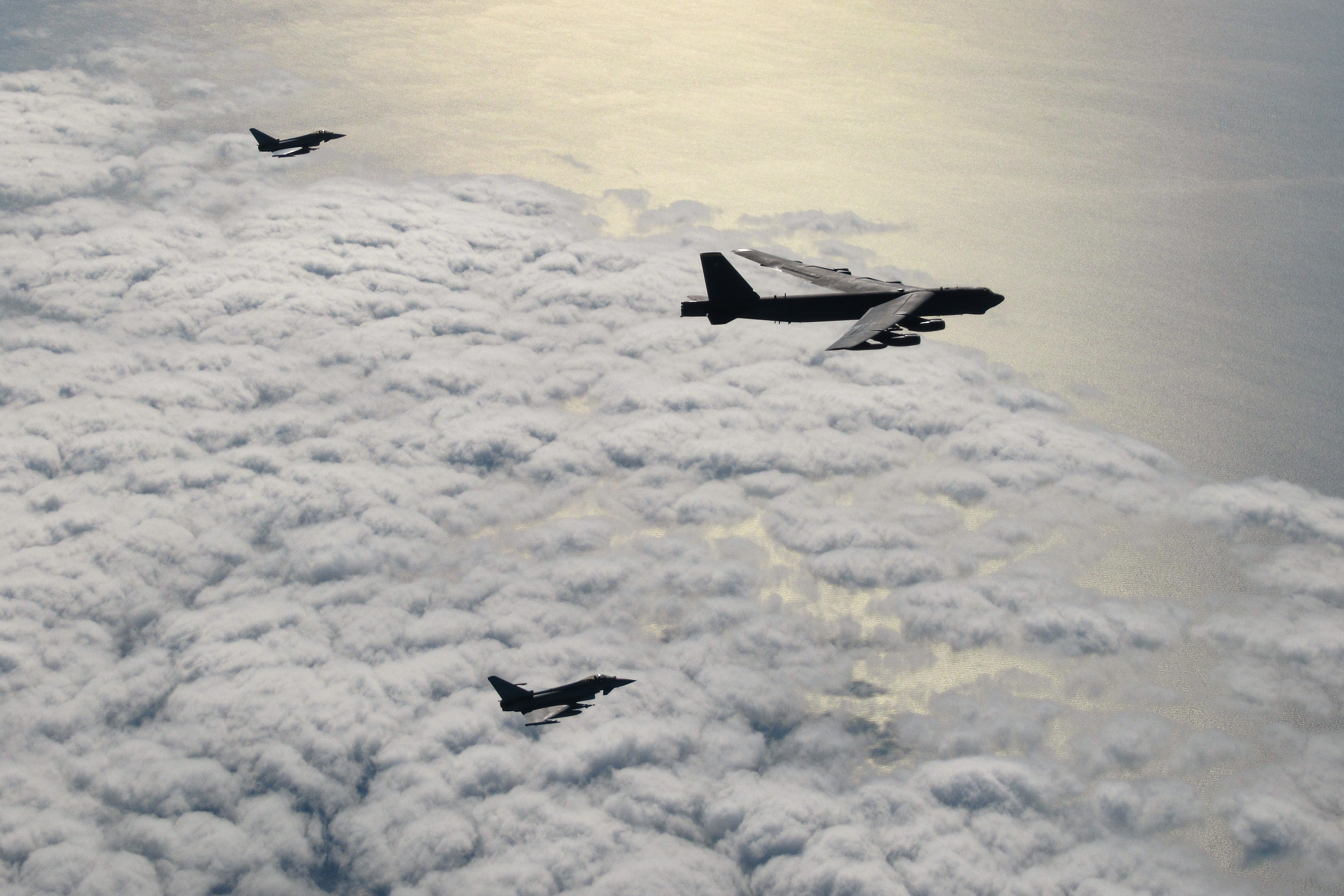 United States Air Force B-52 bomber and two RAF Typhoons above the clouds.